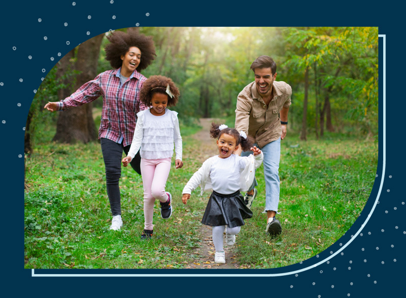 A family running through the park together laughing.